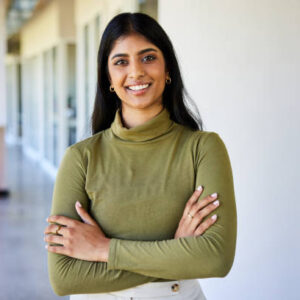 Testimonial1 Portrait of a confident businesswoman smiling while standing with her arms crossed in the bright hallway of a modern office